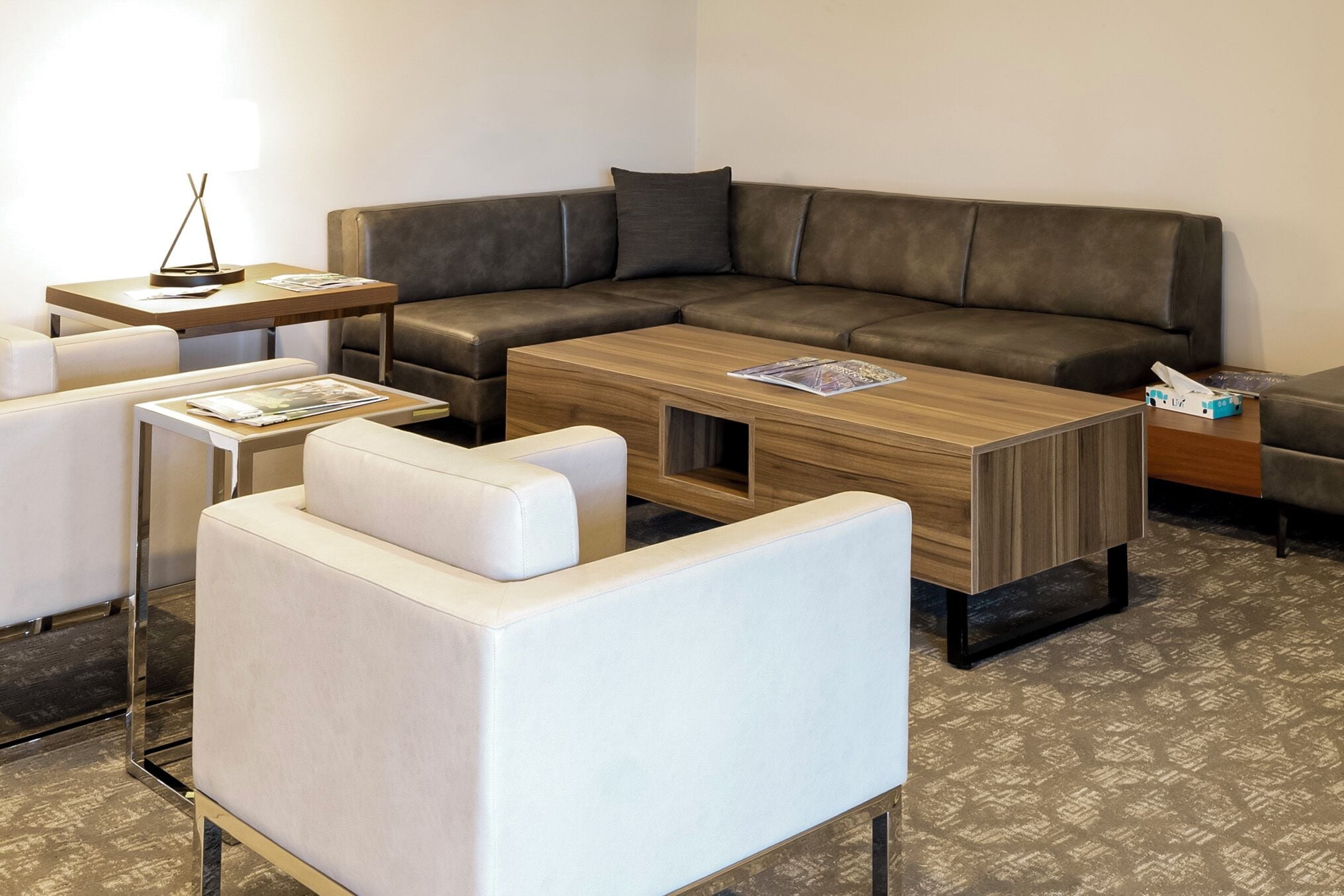 A modern living room with a sectional sofa, a wooden coffee table, and a white armchair.