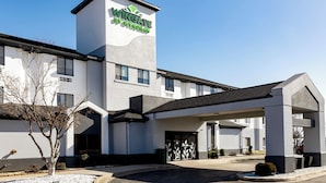 A Wingate by Wyndham hotel with a modern design, featuring a prominent tower with the hotel name, a covered entrance, and a parking area.
