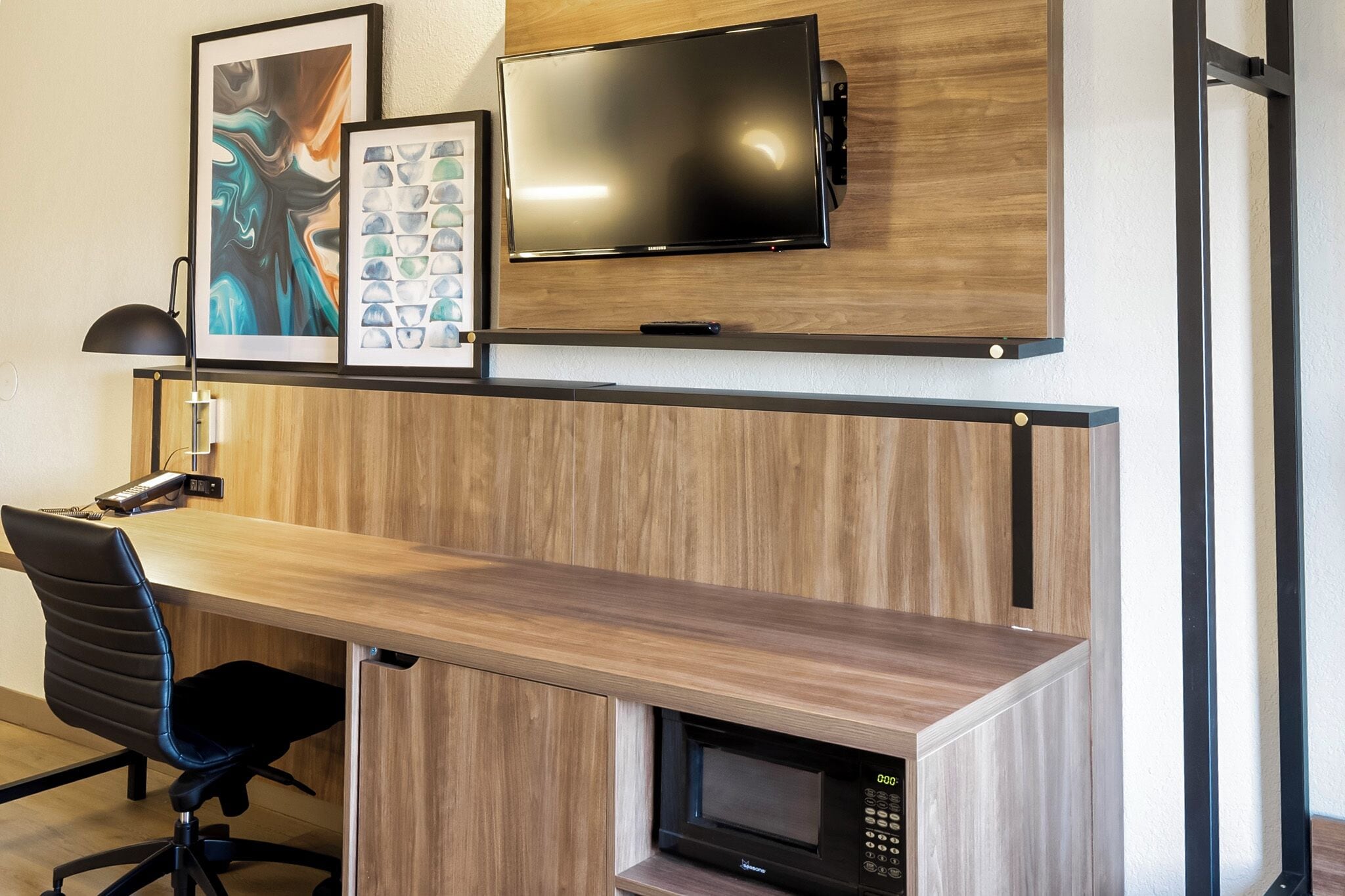 Una cocina moderna con microondas integrado, un televisor de pantalla plana montado en una pared de madera y un escritorio con una silla.