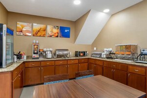 Una cocina con armarios de madera, encimera de granito y varios electrodomésticos, incluyendo una cafetera, microondas y tostadora.