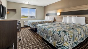 Ett hotellrum med två sängar, ett skrivbord, en TV, ett fönster med utsikt och ett mönstrat golv.