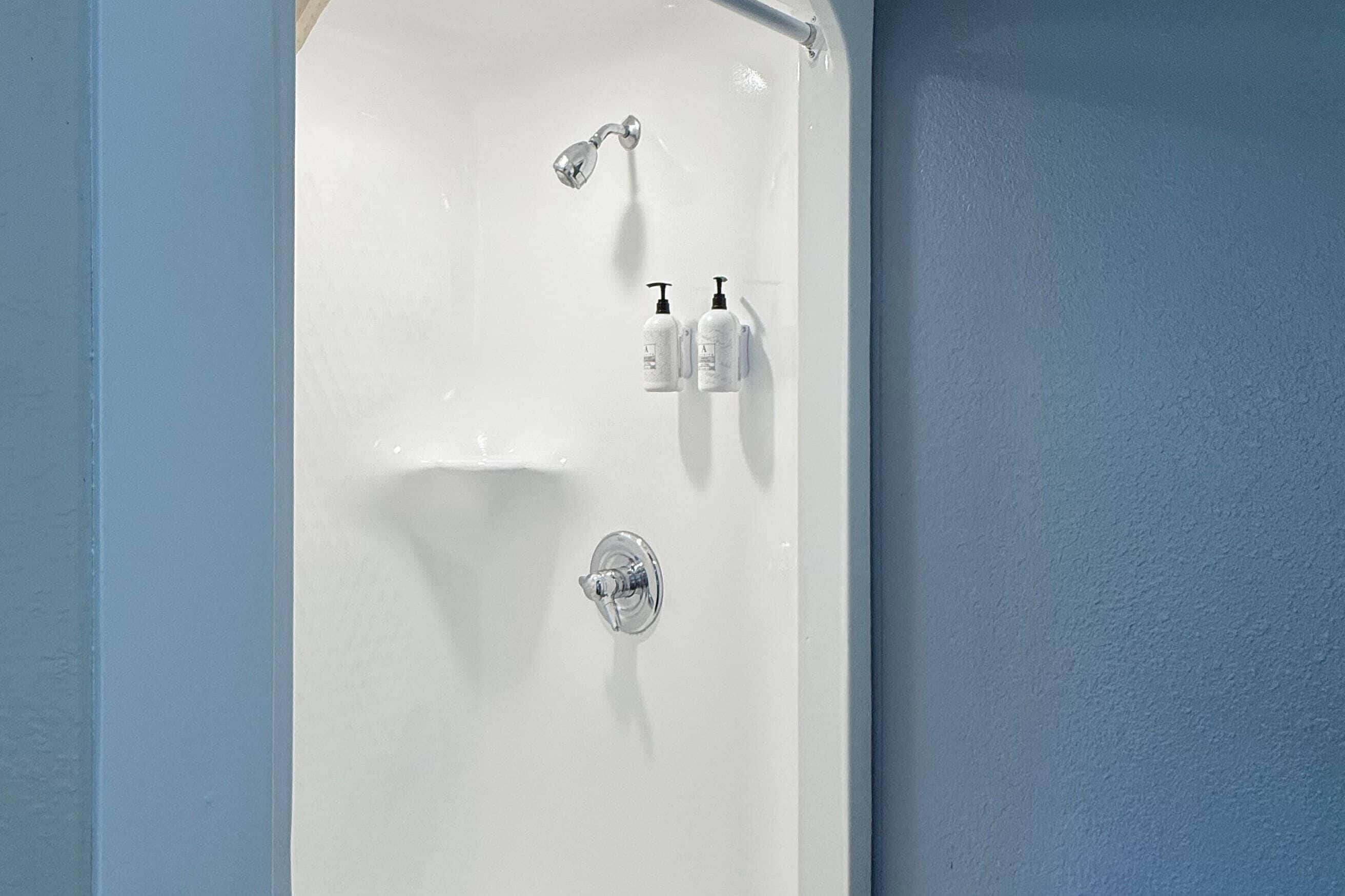 A bathtub with a showerhead, two bottles of toiletries, and a faucet.