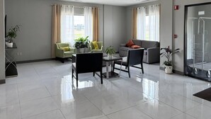 En modern hotellobby med en sittgrupp, en glasvägg och en krukväxt.
