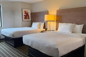 A hotel room with two beds, a nightstand with a lamp, a framed picture on the wall, and a patterned floor. - Sleep Inn & Suites Peoria North (Peoria)