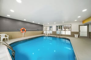 An indoor swimming pool with a lifebuoy, chairs, and a changing room. - Comfort Inn Plainfield - Indianapolis Airport (Plainfield)