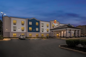 Un hotel Comfort Inn con un edificio de dos pisos, un estacionamiento y una entrada bien iluminada.