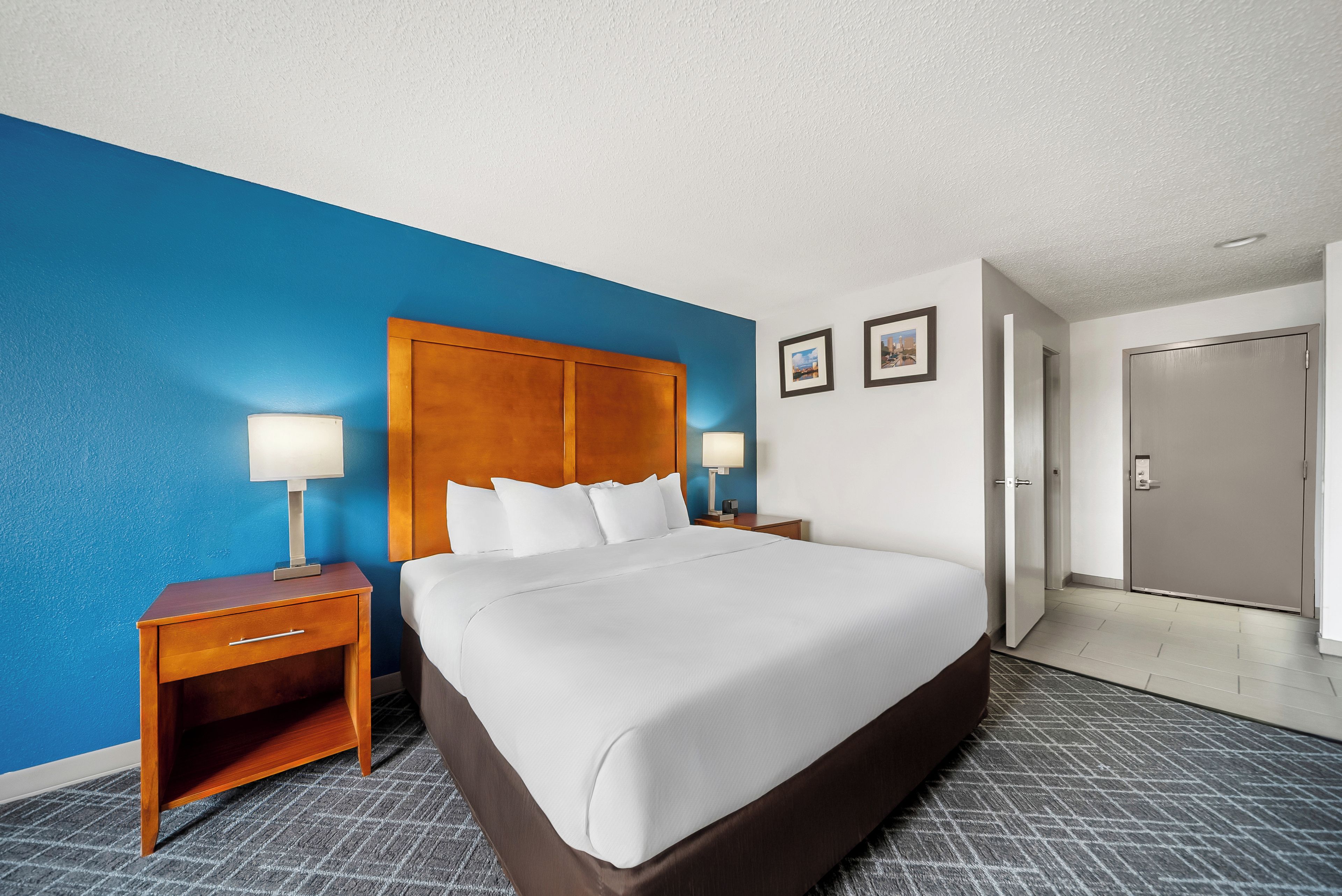 A hotel room with a large bed, two bedside tables, a wardrobe, and a door.
