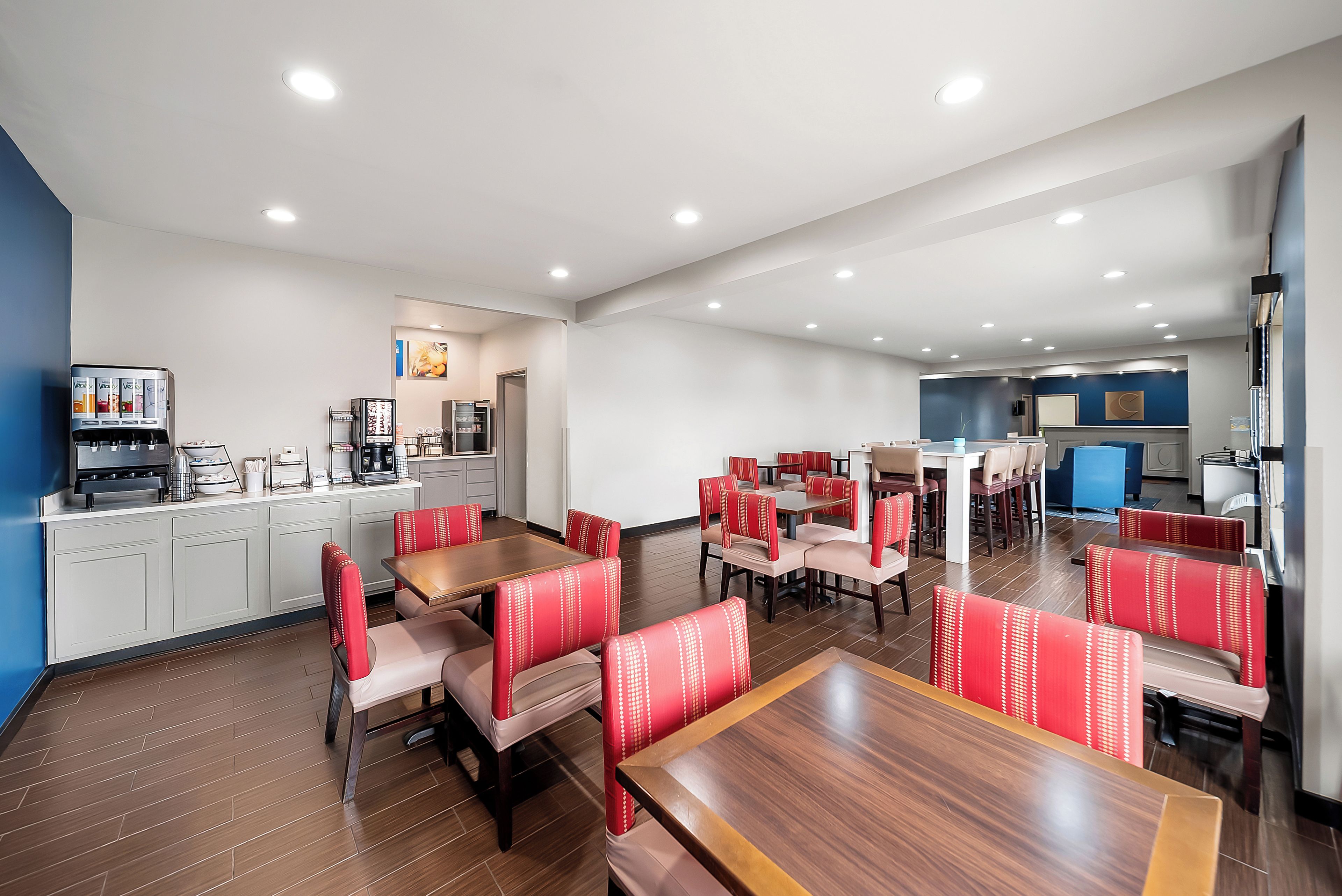 A hotel dining area with multiple tables and booths, a coffee machine, and a refrigerator.