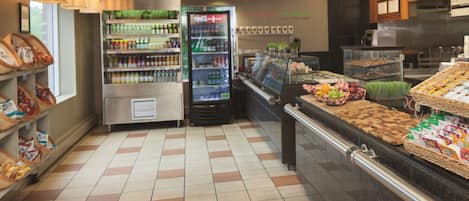 A self-service beverage station with refrigerated drinks and snacks, a bakery display, and a counter with packaged goods.