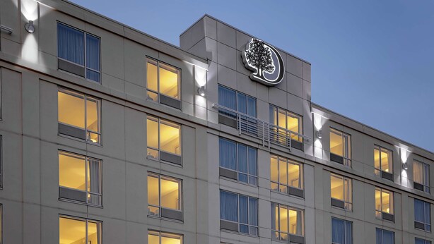 A multi-story hotel with illuminated windows and a prominent logo on the facade. - DoubleTree by Hilton Hotel Boston Bayside (Boston)