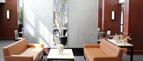 Un vestíbulo con dos sofás naranja, una mesa blanca y un jarrón decorativo.