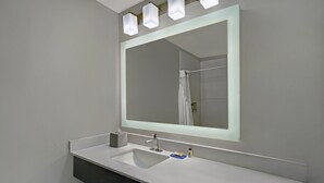 A modern bathroom with a large mirror, a white sink, and a dark vanity. - Holiday Inn Express Adrian by IHG (Adrian)
