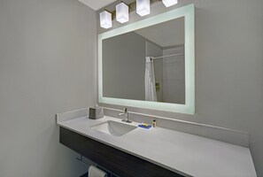 Een moderne badkamer met een grote spiegel, een witte wastafel en een donkere badkamermeubel.