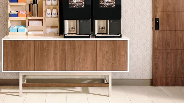 A modern kitchen with a wooden cabinet, a coffee machine, and storage boxes. - Holiday Inn Express Adrian by IHG (Adrian)