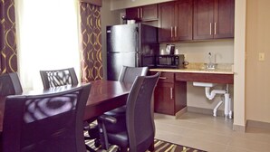 A modern kitchen with dark wooden cabinets, a stainless steel refrigerator, a microwave, and a sink under the counter. - Holiday Inn Express Adrian by IHG (Adrian)