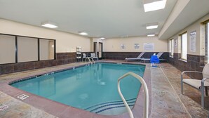 An indoor swimming pool with a tiled floor, a pool ladder, and lounge chairs. - Holiday Inn Express Adrian by IHG (Adrian)