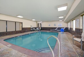 An indoor swimming pool with a tiled floor, a pool ladder, and lounge chairs. - Holiday Inn Express Adrian by IHG (Adrian)