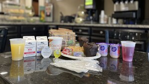 A kitchen counter with various food items and beverages, including cartons of milk, a plate of brownies, and several cups. - Quality Inn & Suites Augusta Fort Gordon Area (Augusta)