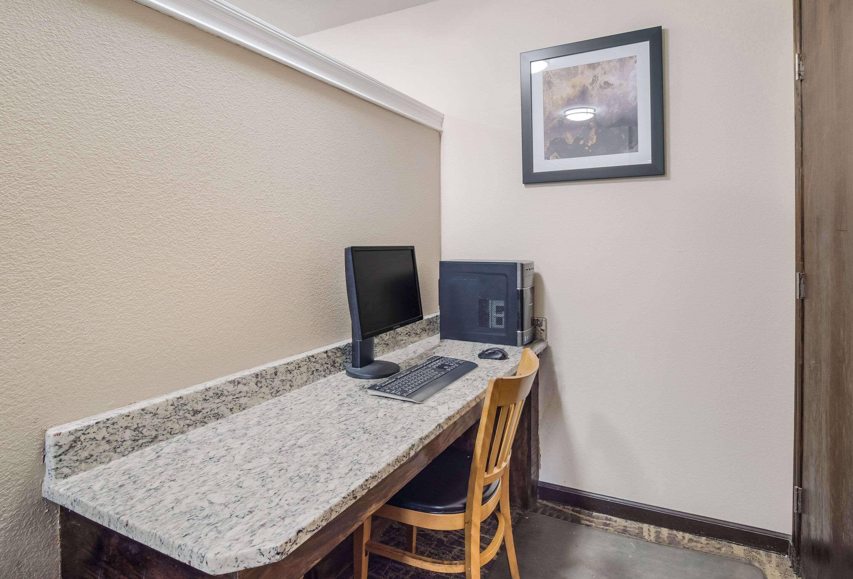 A small office space with a desk, two monitors, a keyboard, and a chair.