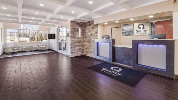 A hotel reception area with a stone accent wall, a reception desk, and a seating area with chairs. - Quality Inn & Suites Augusta Fort Gordon Area (Augusta)