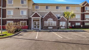 A multi-story hotel with a central entrance, a parking lot, and a small garden area. - Quality Inn & Suites Augusta Fort Gordon Area (Augusta)
