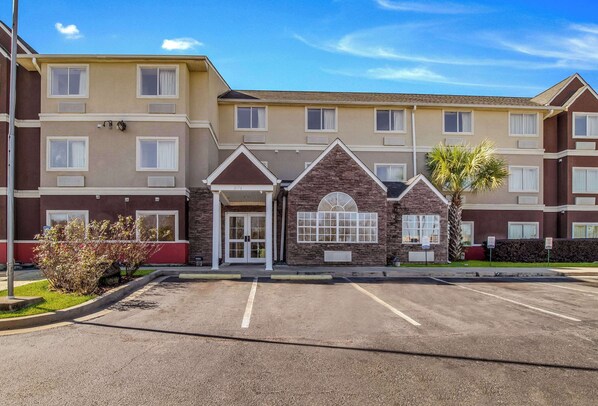 A multi-story hotel with a central entrance, a parking lot, and a small garden area. - Quality Inn & Suites Augusta Fort Gordon Area (Augusta)