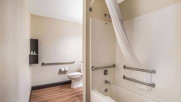 A bathroom with a shower, toilet, and a handrail.