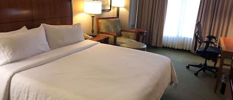 Een hotelkamer met een groot bed, een bureau, een stoel en een lamp.