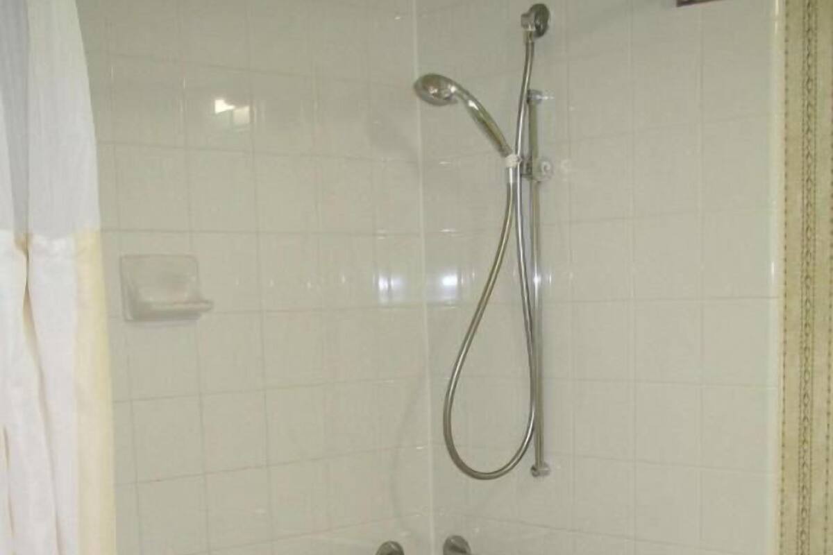Un baño con bañera, ducha y barras de apoyo.