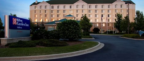 A Hilton Garden Inn with a large building, a sign indicating the entrance, and a well-maintained lawn.