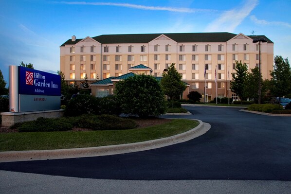 A Hilton Garden Inn with a large building, a sign indicating the entrance, and a well-maintained lawn. - Hilton Garden Inn Addison (Addison)