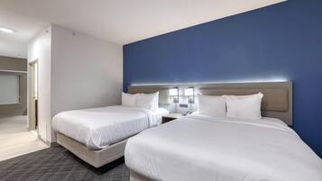 A hotel room with two beds, a blue accent wall, and a neutral color scheme.