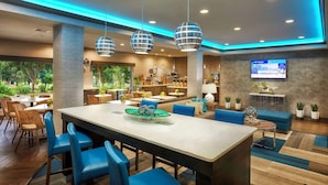 A modern hotel lobby with a large reception desk, blue seating, and a TV screen. - Best Western Plus Lewisville Flower Mound (Lewisville)