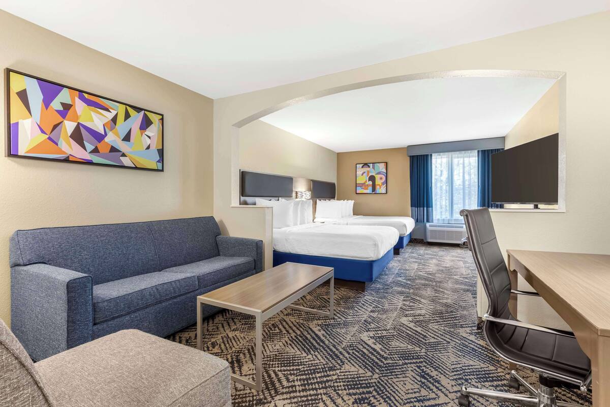 A hotel room with a sofa, a bed, a desk, and a chair.