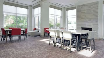 A spacious conference room with large windows, a fireplace, and a carpeted floor.