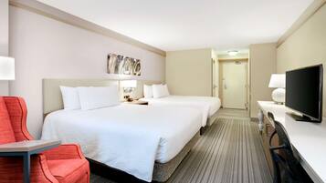 Une chambre d’hôtel avec deux lits, un bureau, une télévision et une chaise rouge.