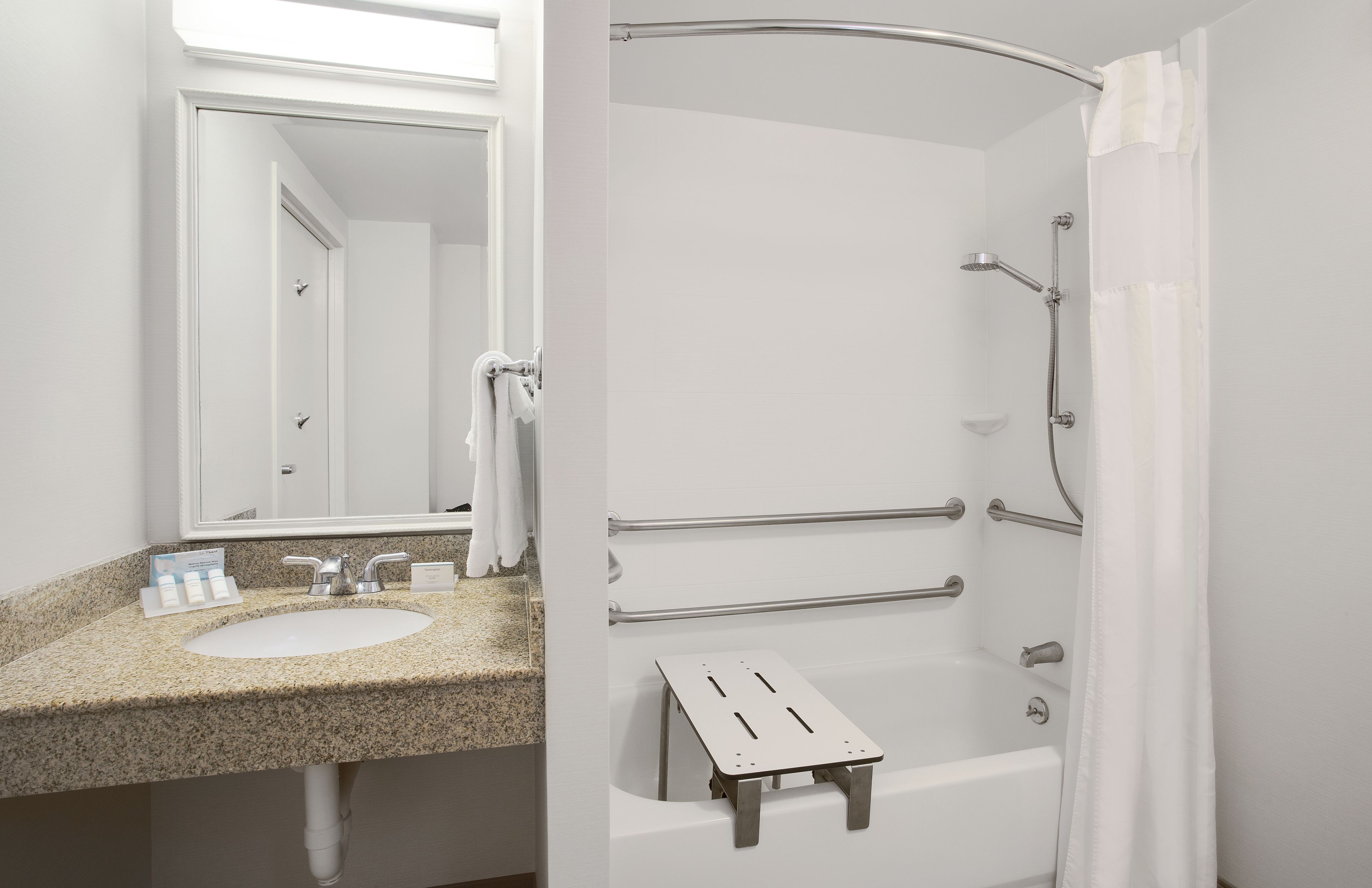 A bathroom with a sink, mirror, and shower area.
