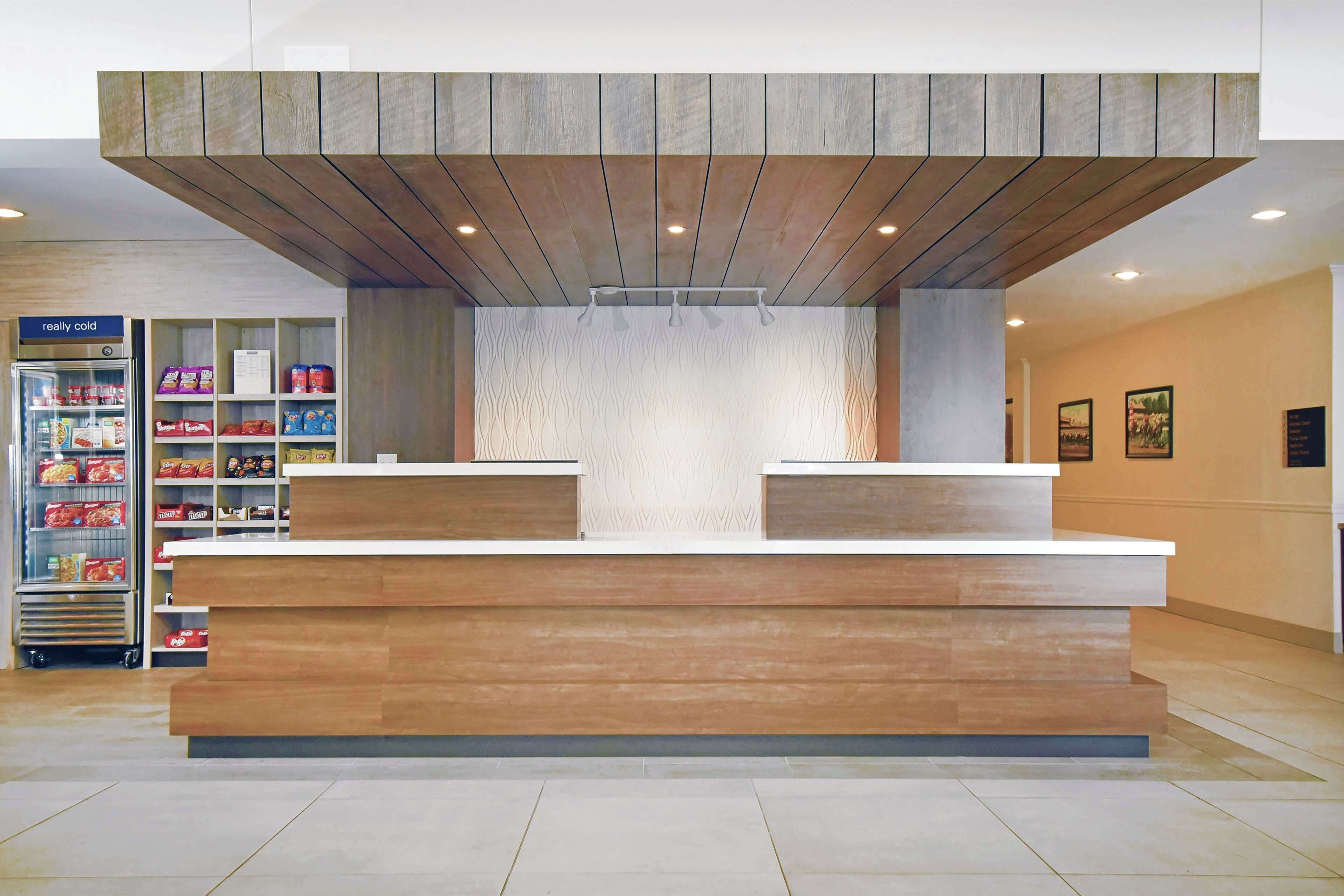 A reception area with a wooden reception desk, a refrigerated display case, and a patterned wall.