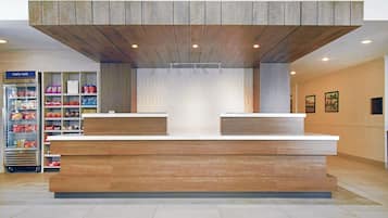 A reception area with a wooden reception desk, a refrigerated display case, and a patterned wall.