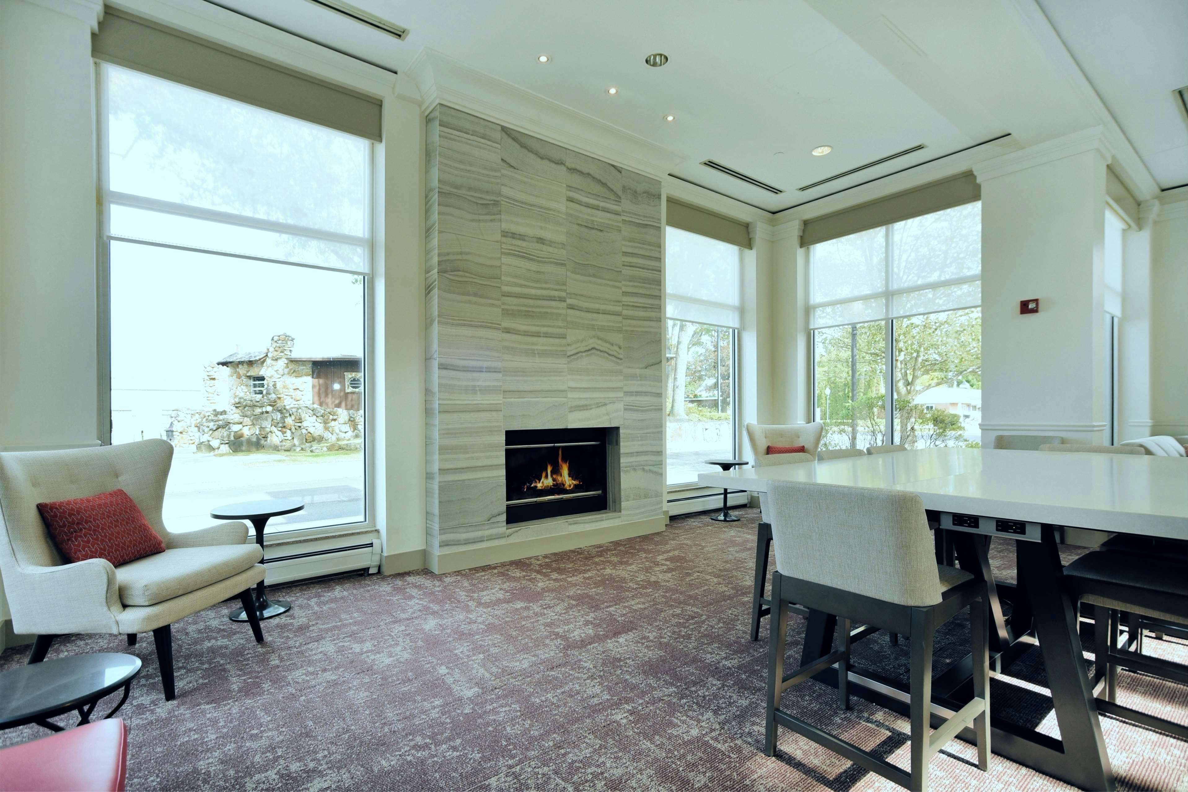 Una sala de estar moderna con chimenea, ventanas amplias y un comedor.