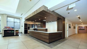 Un hall d’entrée spacieux avec un comptoir d’accueil central, une grande fenêtre et un aménagement intérieur moderne.