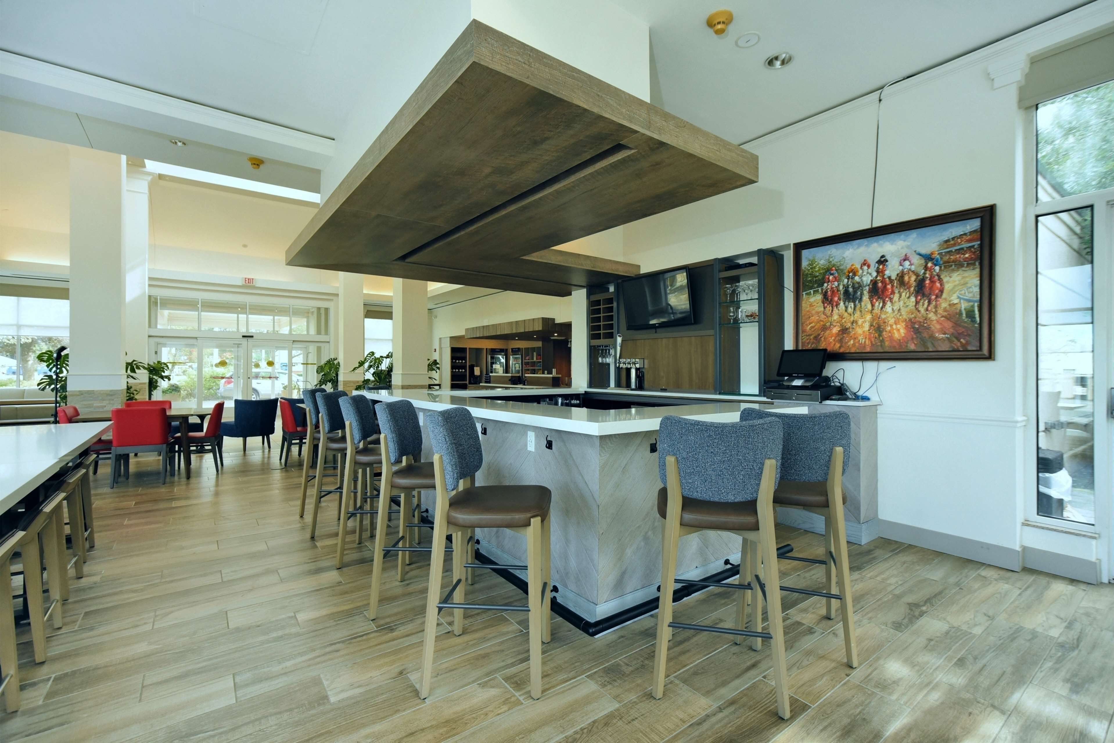 Una cocina moderna con una isla central, taburetes de bar y un cuadro grande en la pared.