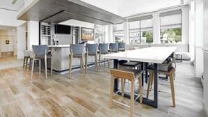 Une cuisine spacieuse dotée d’un grand îlot central, de chaises modernes et d’un coin repas avec une longue table.