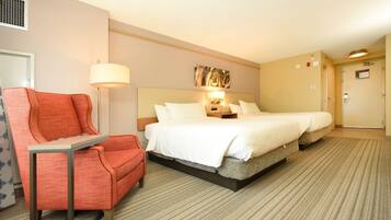 A hotel room with a bed, a chair, a lamp, and a door.