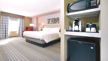 A hotel room with a bed, a desk, a microwave, and a coffee maker.