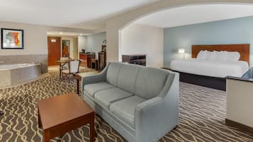 A hotel room with a bed, a sofa, a desk, a chair, a coffee table, and a bathroom with a bathtub.