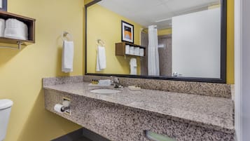 A bathroom with a granite countertop, a sink, a toilet, a towel rack, and a mirror.
