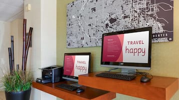 Ein Empfangsschalter mit zwei Monitoren, einer Tastatur und einer Maus. Eine Topfpflanze befindet sich links, dahinter ist eine Stadtkarte an der Wand angebracht.