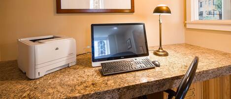 A desktop computer with a monitor, keyboard, and HP printer on a granite countertop.