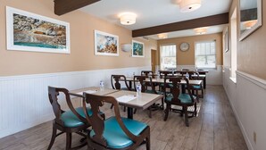A dining area with wooden tables and chairs, framed artwork on the walls, and a clock on the wall. - Best Western Plus Plaza Hotel (Thermopolis)